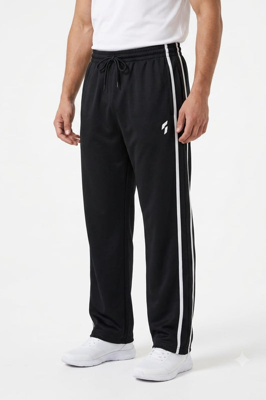 A person wearing black athletic sweatpants with white side stripes and a white drawstring, paired with a white shirt and white sneakers, photographed against a clean white studio background.