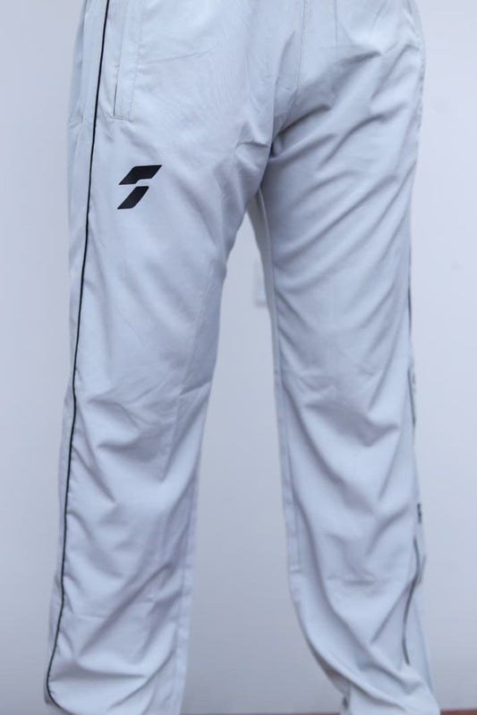 White athletic pants with a black stylized logo on the left thigh and a thin black side stripe, shown against a plain light background.